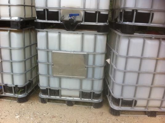ถังพลาสติกสีเหลี่ยมขาวขนาดบรรจุ 1000 ลิตร พร้อมกรงเสริมความแข็งแรงวางบนแผ่นพาเลส
