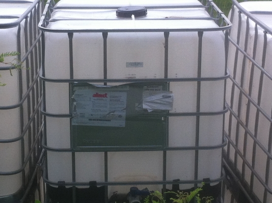 ถังพลาสติกสีเหลี่ยมขาวขนาดบรรจุ 1000 ลิตร พร้อมกรงเสริมความแข็งแรงวางบนแผ่นพาเลส